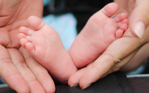 Petits pieds de bébé tenus par des mains d'adulte