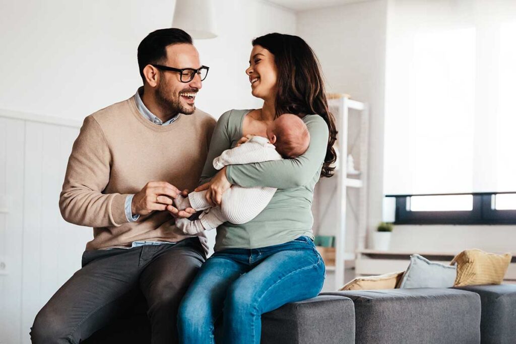 Un couple de parents et leur bébé sont dans leur salon